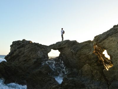 man standing on brown rock formations